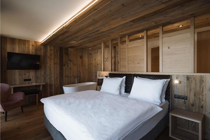 Doppelzimmer Lifestyle mit Einrichtung aus Altholz und freistehender Badewanne