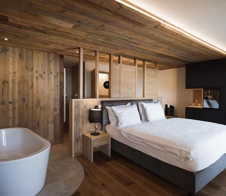 Doppelzimmer Lifestyle mit Einrichtung aus Altholz und freistehender Badewanne